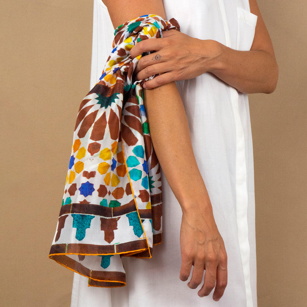Pañuelo amarillo y marrón con estampado inspirado en los mosaicos de La Alhambra en el brazo de una mujer